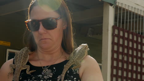 woman holds onto two australian bearded dragon lizards