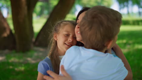 children hugging happy mother close up. lovely family picnic in park meadow.