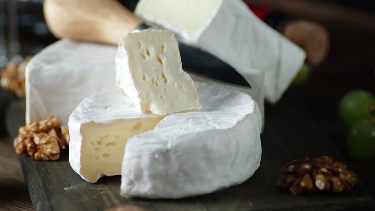Slices of Camembert cheese on cutting Board slowly rotate.