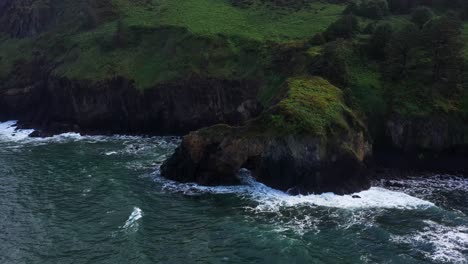 scenic aerial orbital view of cliffs and forest over pacific ocean on the rugged coast of california.