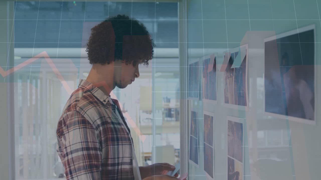Designer approaching wall, studying top row, adjusting sticky notes and aligning prints for layout