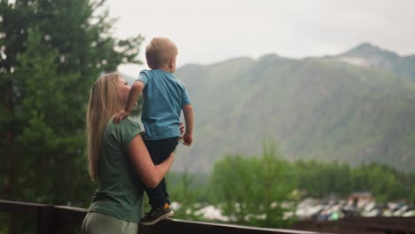 mother with little boy look at old mountain on hotel terrace