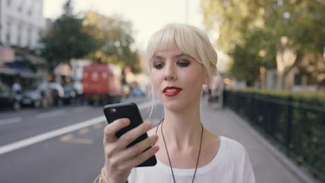 hermosa rubia usando teléfono inteligente en la ciudad