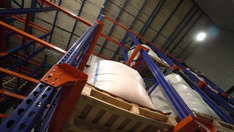 A-warehouse-shelf-laden-with-neatly-stacked-pallets,-heavy-white-bags-placed-on-top