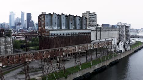 aerial view of rusted industrial silos with a modern city skyline backdrop. a stunning contrast of urban decay and sleek architecture. montreal's old port docks.