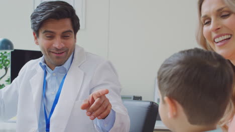 un médico sonriente o un médico de cabecera blanca se reúnen madre e hijo para una cita en la oficina