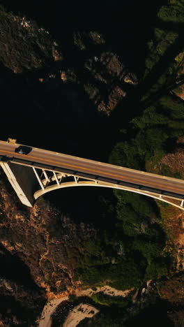 road on the bridge over the gap between the mountains. descending above the beautiful bridge construction on sunny day. view from top. vertical video