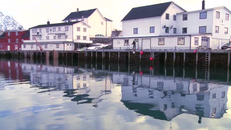 Snow-covered-mountains-are-reflected-in-a-harbor-in-a-small-fishing-village-in-the-Arctic-Lofoten-Islands-Norway-3