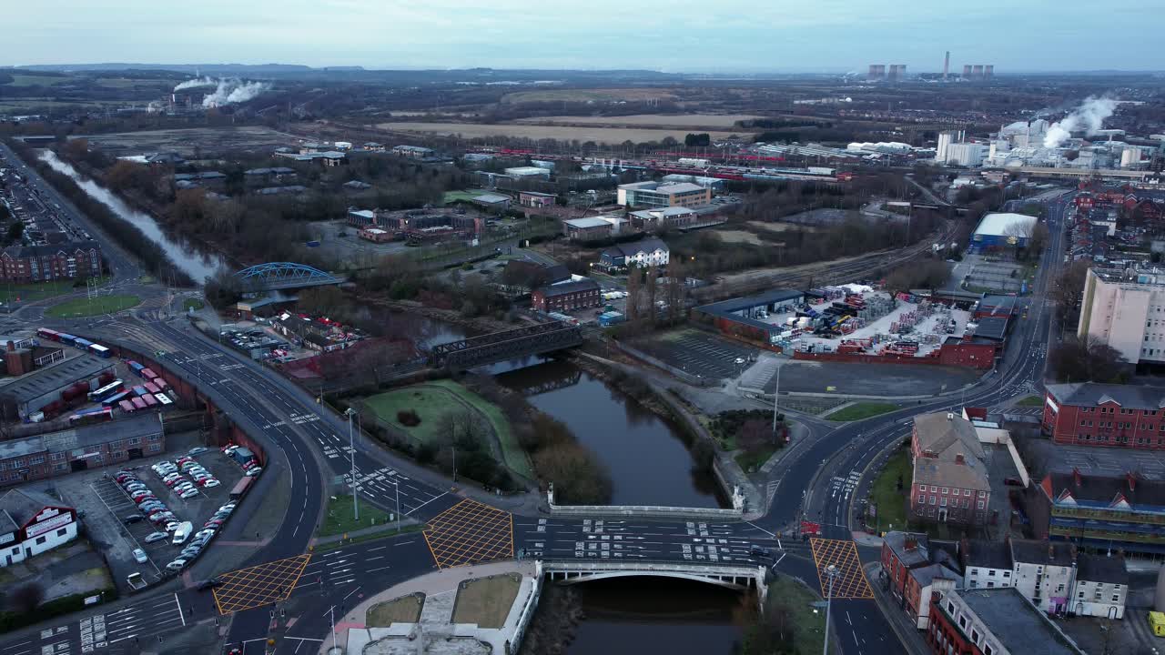 Aerial early morning city street traffic commuting intersection lanes crossing curved river slow descend