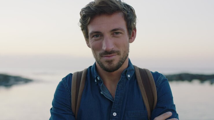 ritratto di un uomo caucasico attraente e affascinante che sorride fiducioso sulla tranquilla spiaggia costiera