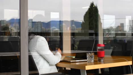 side view of young asian businesswoman writing on notepad and working on laptop in office 4k