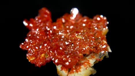 검은색 배경 앞에 오렌지색 광물 (바나디나이트) 을 원활하게 회전시니다.