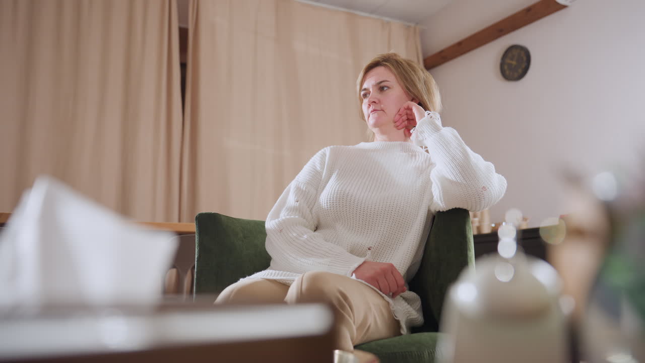 Mental care specialist nodding attentively during therapy session in warm setting with tissue box and wall clock visible, expressing active listening, and professionalism in calm therapeutic space