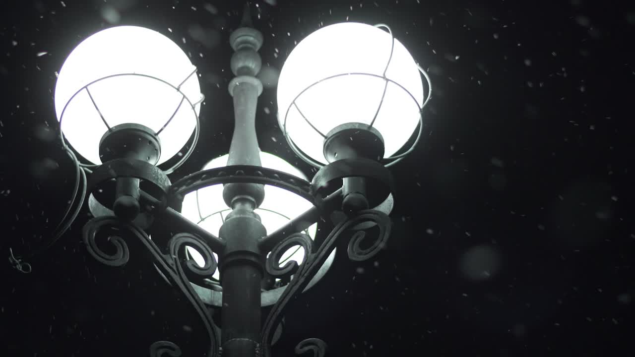 светящийся уличный фонарь в снежную ночь. крупный план уличного фонаря в ночных снежинках