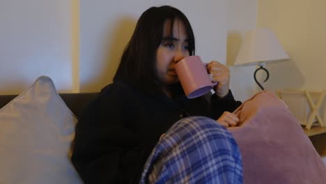 portrait of a young woman watching television at home inside the bedroom