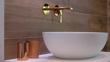 slow orbiting shot of a luxury wash basin with a wooden splashback in a toilet