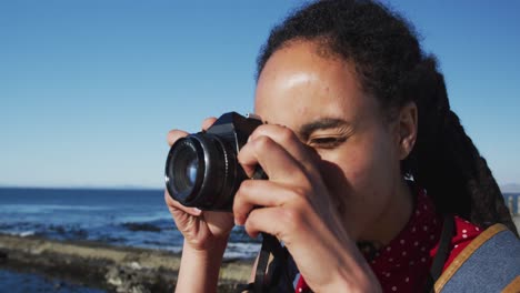 mujer afroamericana fotografiando en el paseo marítimo por el mar