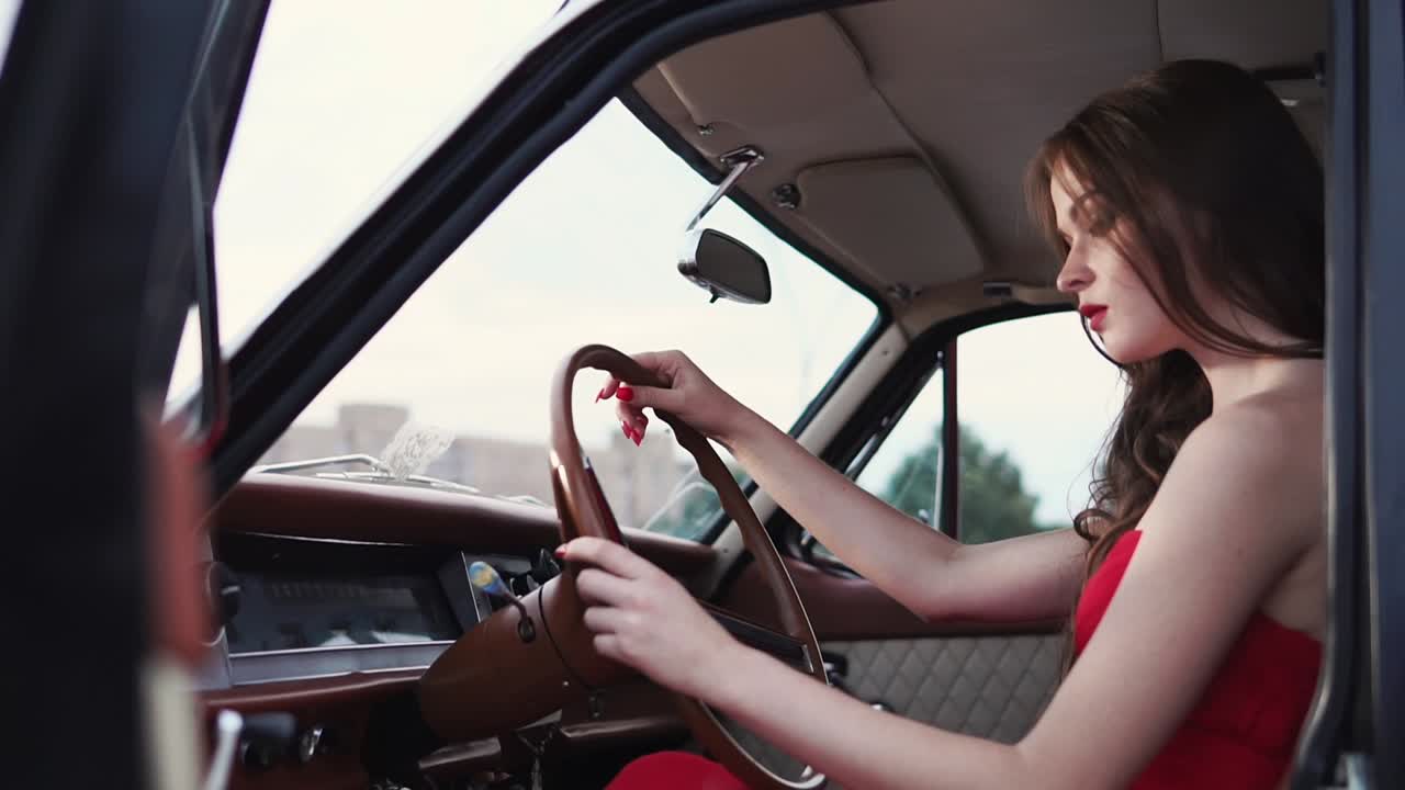 Woman Driving a Vintage Car in a Red Dress