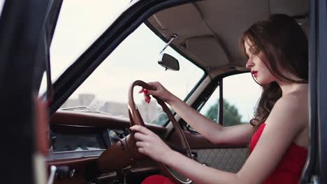 woman driving a vintage car in a red dress