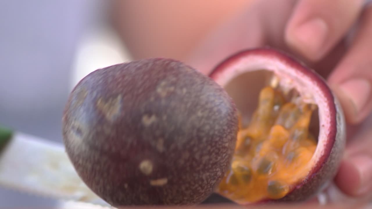 Skærer en frugthalvdel på et træbræt i slowmotion