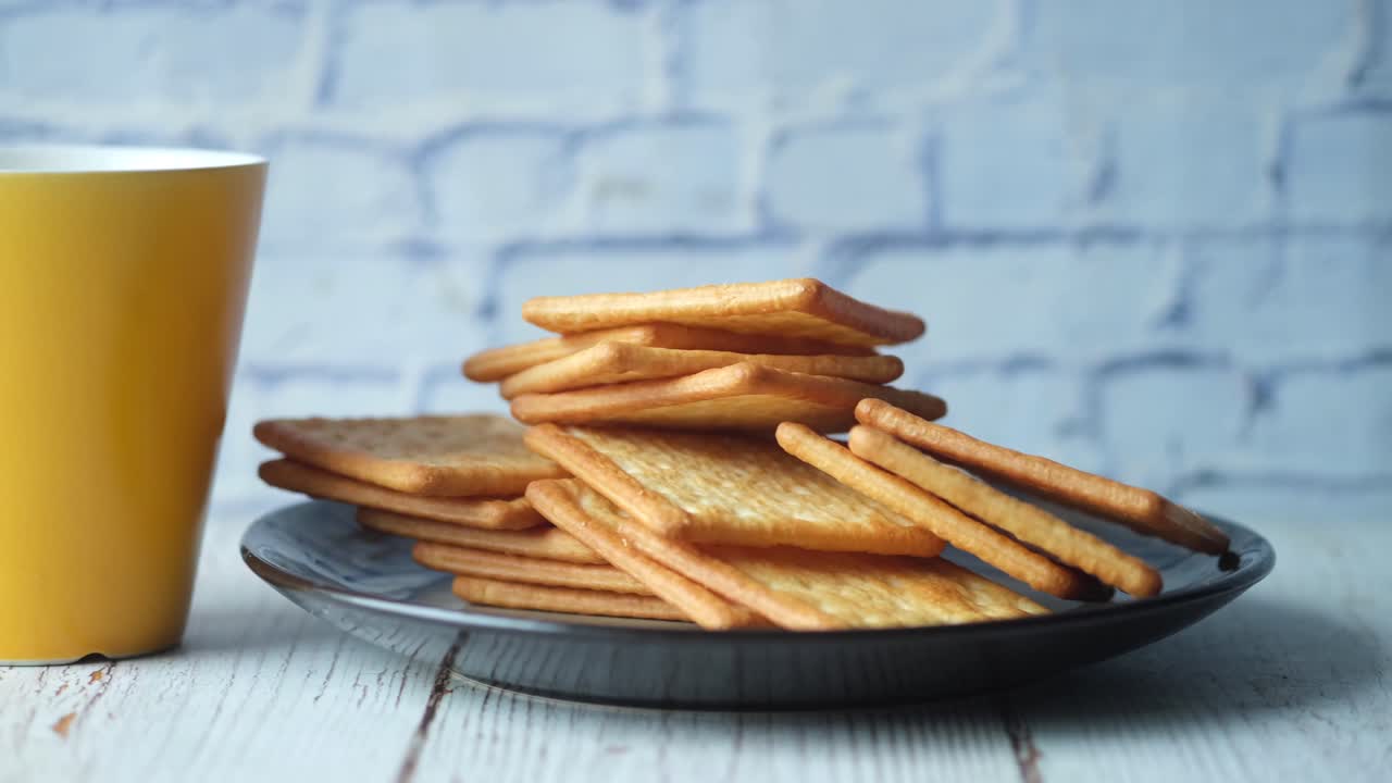 Pila di cracker su un piatto con una tazza gialla