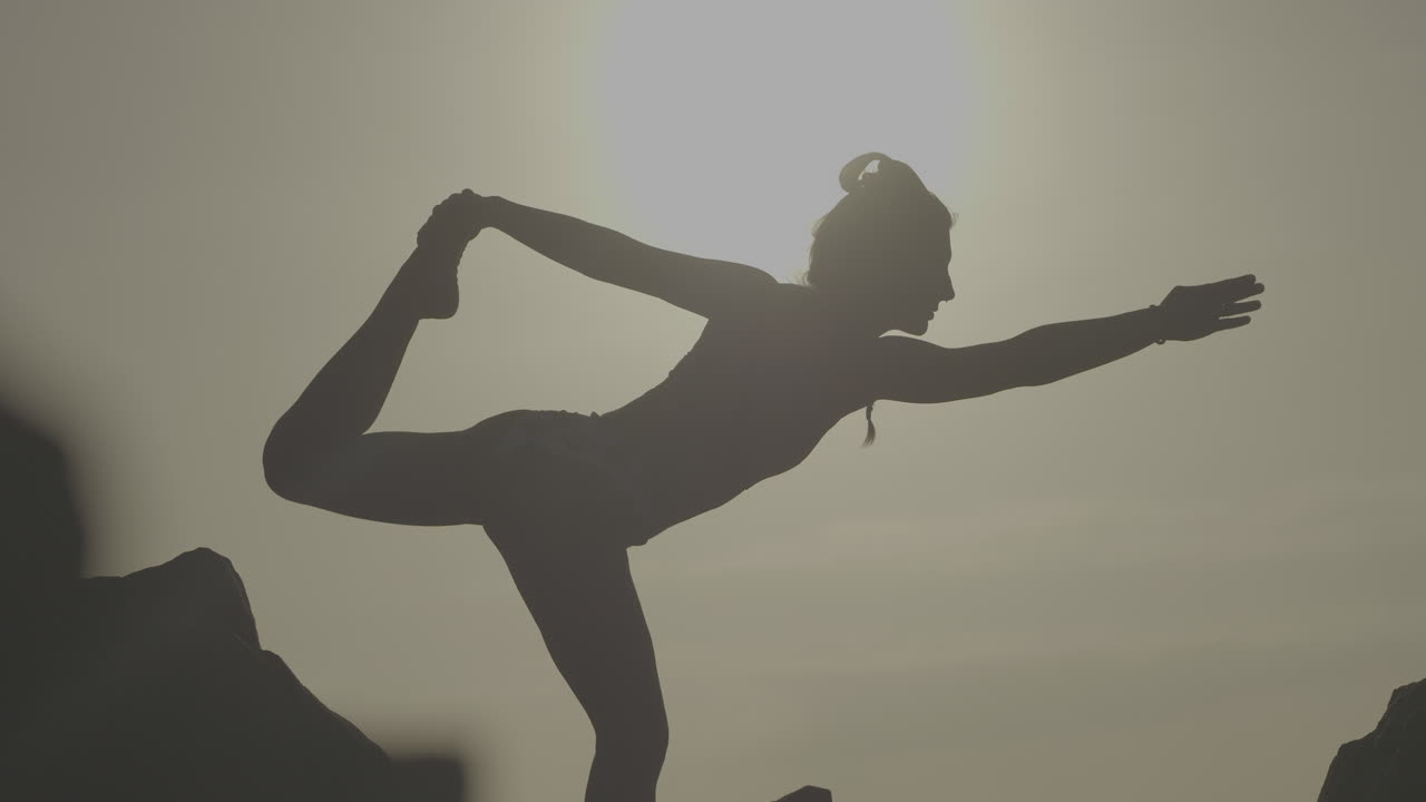 Woman practicing yoga outdoors at sunrise