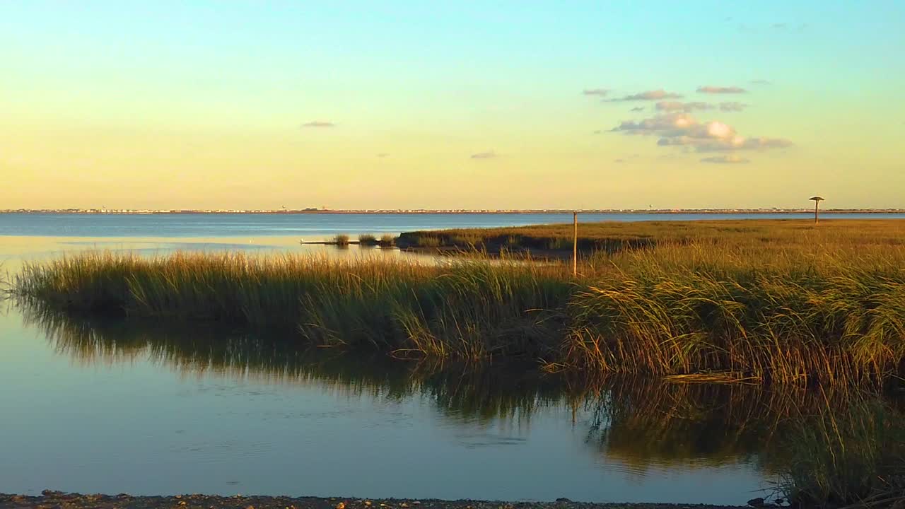 hd 120 fps panorámica de izquierda a derecha desde la vista de la vía fluvial más allá del horizonte de la ciudad atlántica en la distancia con cielo mayormente despejado cerca de la hora dorada