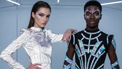 stunning fashion showcase featuring two models in striking reflective outfits with intricate face art, capturing the essence of modern design and style