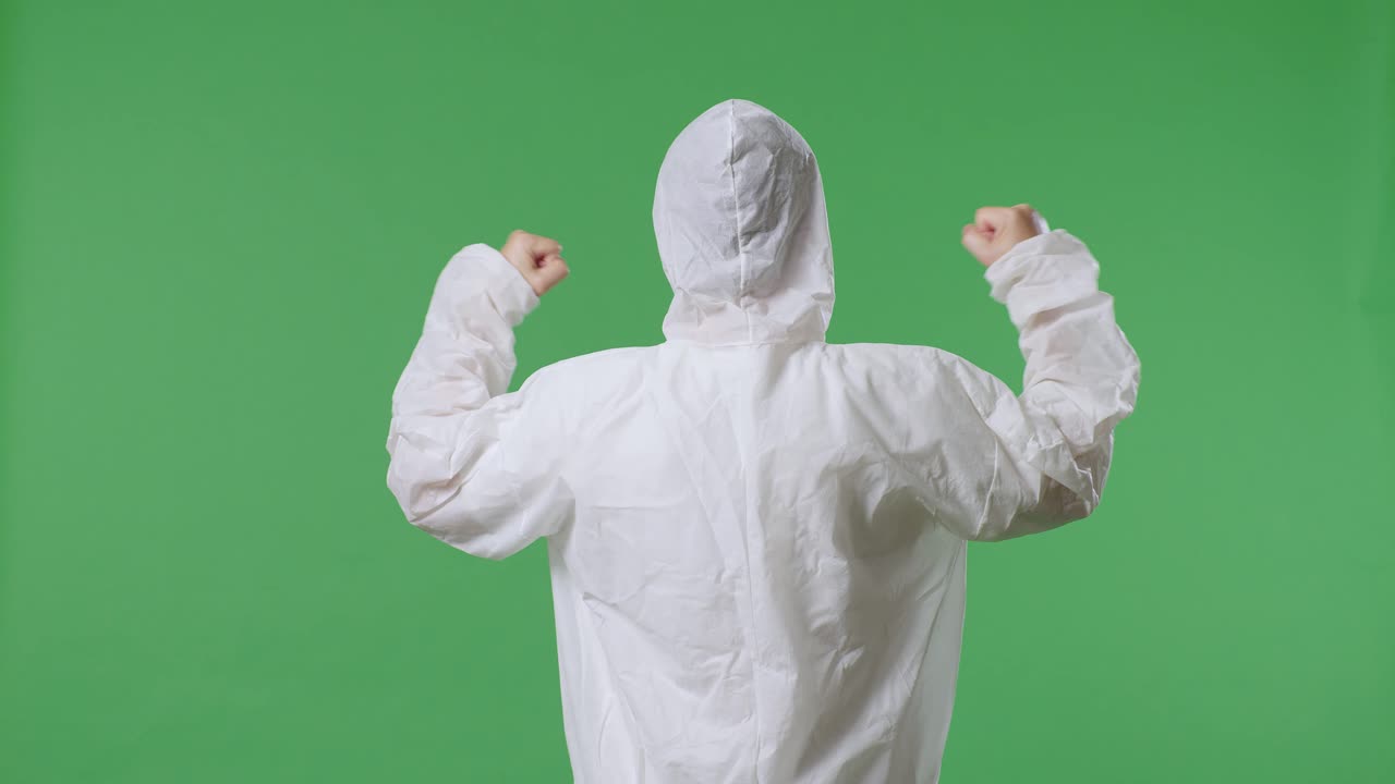 vista trasera del científico masculino asiático celebrando el éxito mientras está de pie en el fondo de la pantalla verde