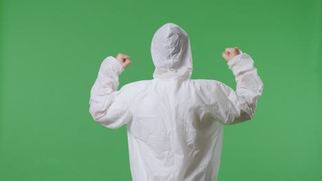 vista trasera del científico masculino asiático celebrando el éxito mientras está de pie en el fondo de la pantalla verde
