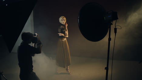 high angle view of caucasian young female model posing in the dark studio while the photographer taking shots of her