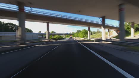 drive pov: following truck through overpasses on sunny highway commute