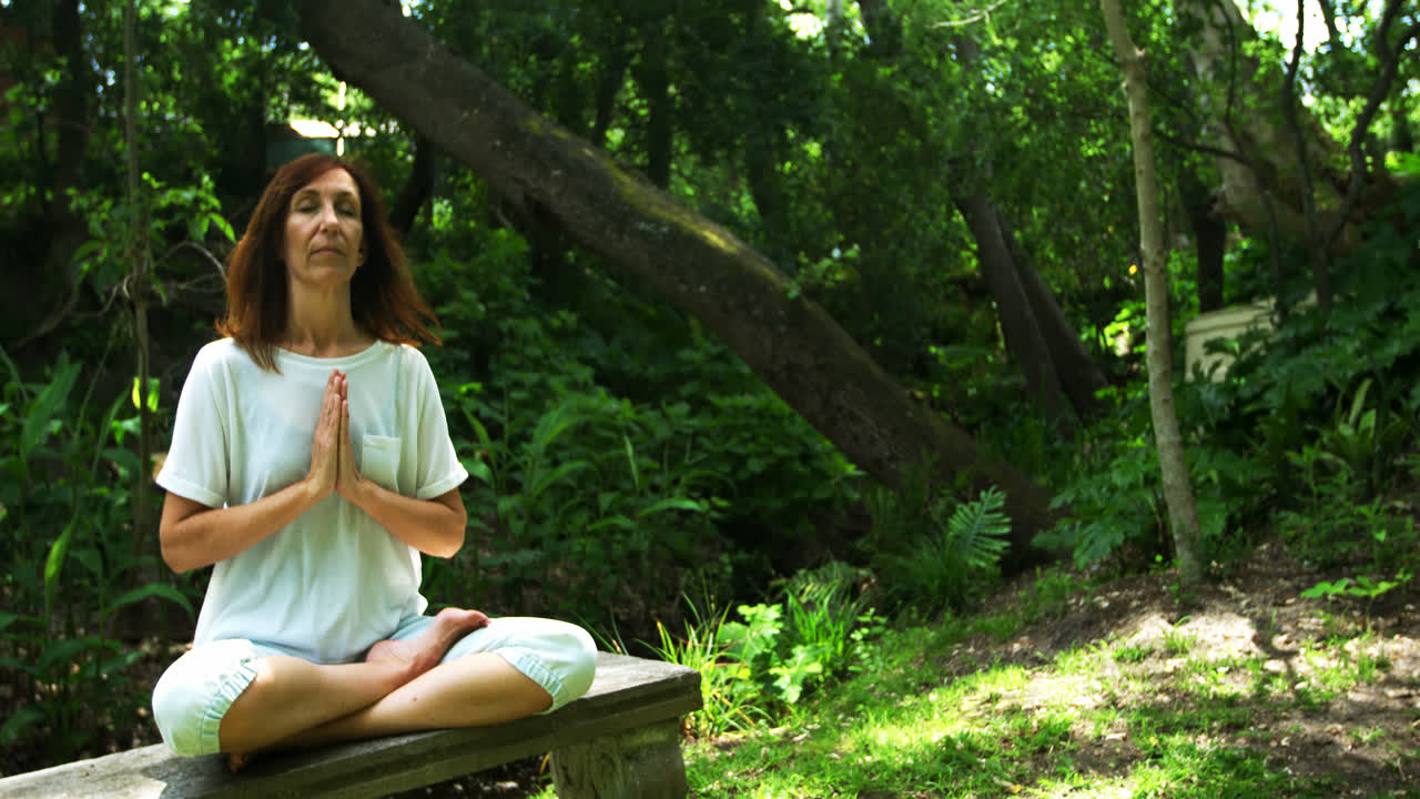 mujer madura haciendo yoga en el parque 4k