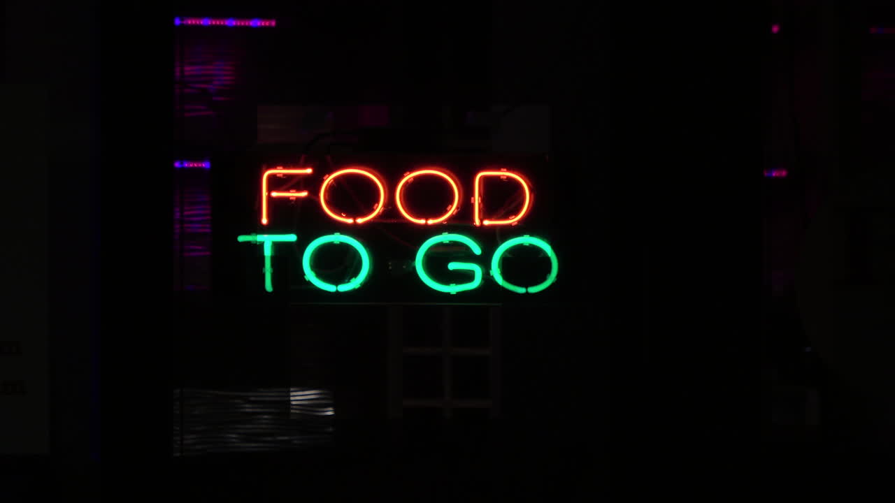 Red green FOOD TO GO sign glows in restaurant window, 4K
