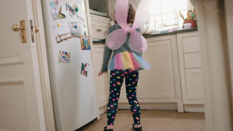 Niña-Feliz-Bailando-En-La-Cocina-Usando-Lindas-Alas-De-Hada-Divirtiéndose-Agitando-Una-Cuchara-Jugando-A-Fingir-Haciendo-Divertidos-Movimientos-De-Baile-Disfrutando-El-Fin-De-Semana-En-Casa