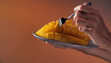 Hand-use-Fork-to-Pick-Up-Craved-Mango,-Close-Up