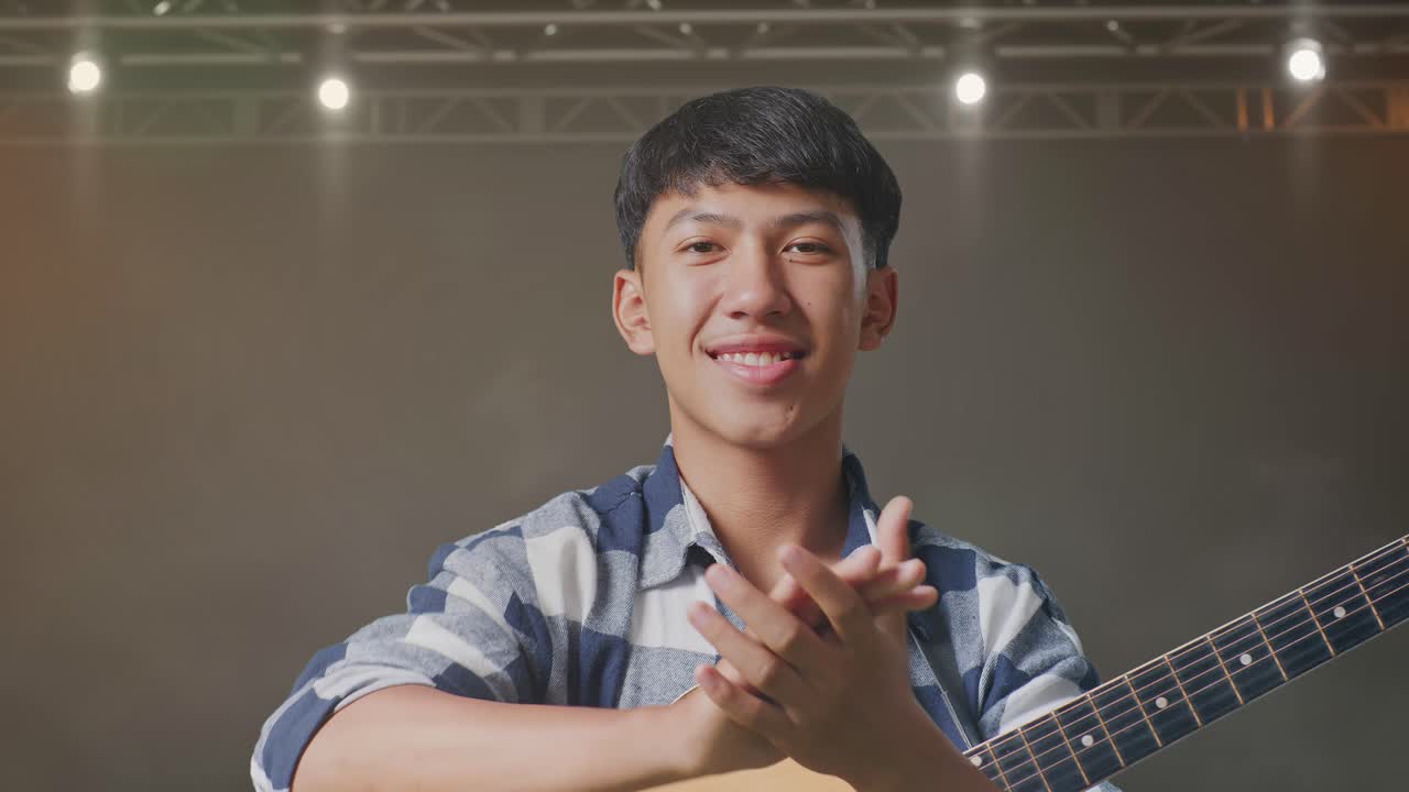 기타를 들고 무대에서 손을 치는 아시아 십대의 클로즈업