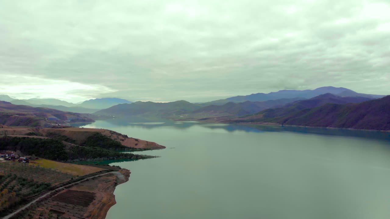 아침에 흐린 하늘 아래 농업 소포로 둘러싸인 평화로운 산 호수