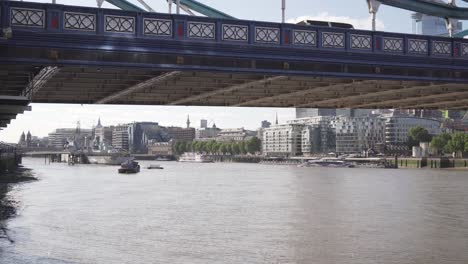 Vista-Cinematográfica-Bajo-El-Puente-De-La-Torre-En-Londres,-Río-Támesis-Y-Barco