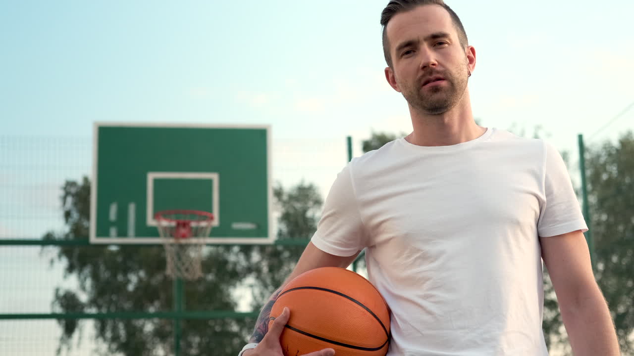 hombre sosteniendo una pelota de baloncesto en una cancha