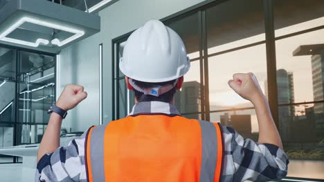 vista posterior de cerca de un ingeniero masculino con casco de seguridad levantando las manos celebrando mientras trabajaba con el proyecto de drones