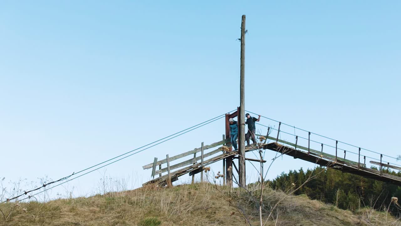 dos personas en un puente de madera en un paisaje rural