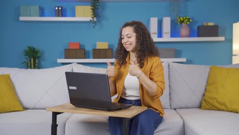 mujer joven mirando la computadora portátil haciendo un gesto positivo.