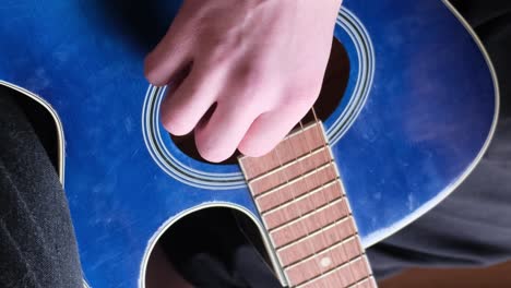 a male musician plays a blue acoustic guitar. modern young hipster guitarist playing guitar. stylish curly hair.