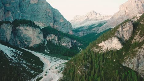 forward aerial shot in the alps of a valley next to rocky cliffs pt