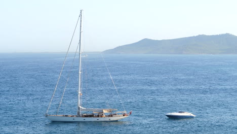 sailboat and speedboat anchored on mediterranean coast. static