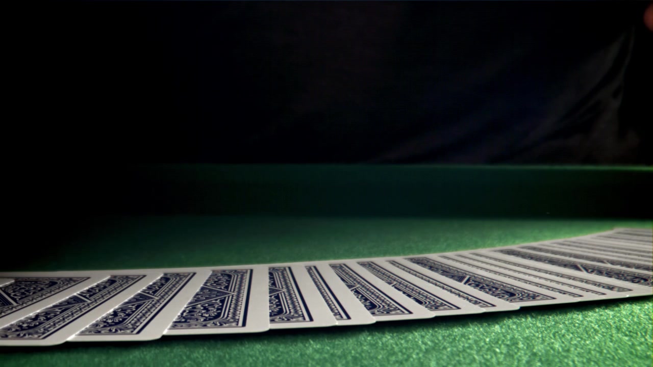 Mano che sventaglia carte da gioco su tavolo di feltro verde