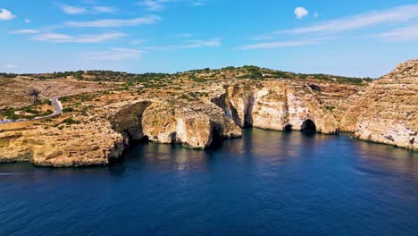 aerial shot of sea arches and cliffs at blue grotto, malta, with boats and stunning coastal rock formations in view.