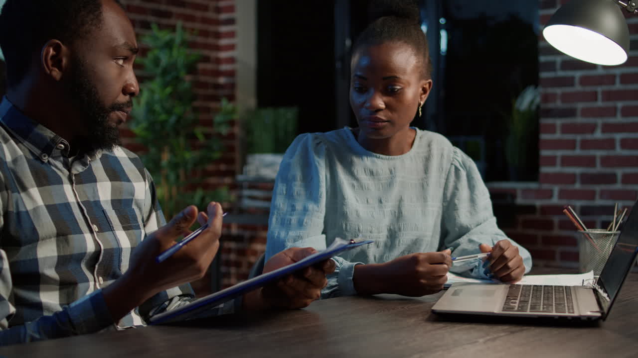 African american team of investors using stock market sales on laptop