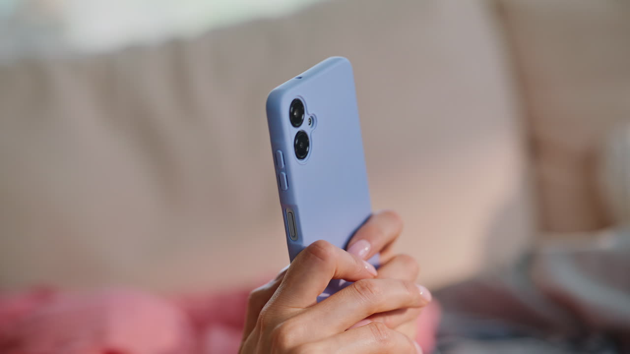 Primo piano di mani di donna che digitano un messaggio su uno smartphone in un appartamento. Signora che invia messaggi